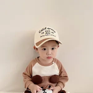 Detailed view of kids color-block baseball cap with letter print and brown waffle shirt