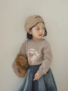 Detail of child wearing a beige beret with 1998 embroidery and a mocha sweater