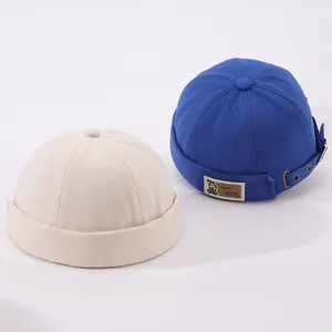 Détail des bonnets docker en coton beige et bleu royal avec boucles métalliques réglables