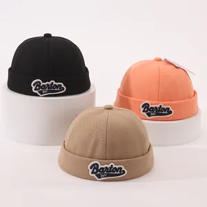 Close-up of cotton brimless dockers caps in black, orange and khaki with letter embroidery