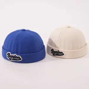 Detail of royal blue and beige cotton docker hats with embroidered Barton 3VF patches