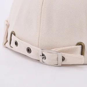 Detail of adjustable metal buckle and twill cotton texture on beige docker hat