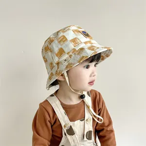 Detalle de gorro de pescador a cuadros para niños con cordón ajustable y parche de cuero