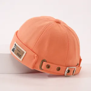 Gros plan du bonnet orange en coton avec écusson en cuir et boucle métallique de réglage