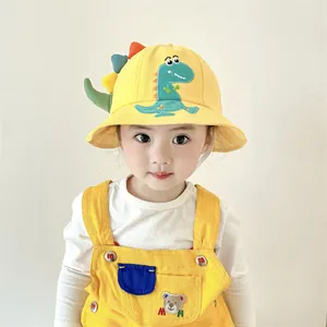 Detail of yellow toddler sun hat with green dinosaur embroidery and matching overalls