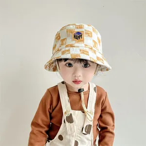 Detalle de gorro de sol para niños a cuadros amarillos con cordón y parche de Happy