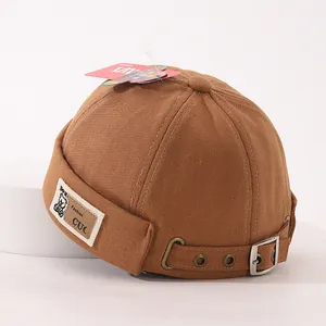 Détail d'un bonnet docker en coton marron avec un écusson en cuir et logo ours cartoon