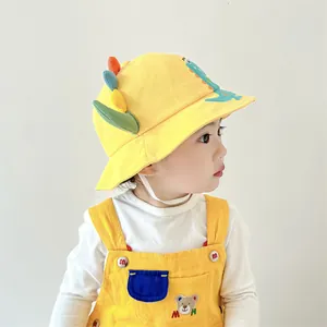 Detail of yellow kids bucket hat with dinosaur spines and a matching bear overall outfit