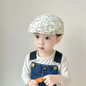Détail du béret bébé beige avec imprimés dinosaures bleu marine et texture douce