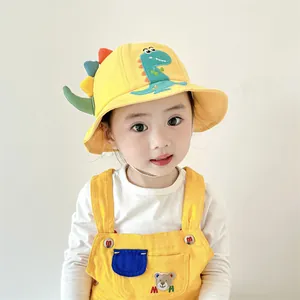 Detail of child wearing a yellow cartoon dinosaur sun hat and matching bear overalls