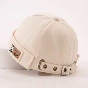 Détail du bonnet docker en coton beige avec patch ours en cuir brun et boucle en métal