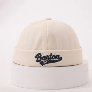 Detailed close-up of cream docker hat showing twill texture and Barton embroidery
