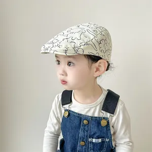 Détail de la casquette bébé avec imprimé dinosaure et boutons de la salopette en jean