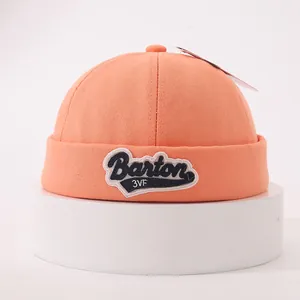 Close-up of orange cotton docker hat with Barton 3VF embroidery on white stand