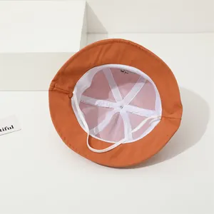 Detail view of the orange bucket hat interior with breathable white mesh lining and strap
