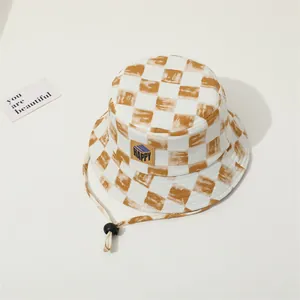Detalle de gorro de pescador a cuadros con parche Happy y cordón ajustable