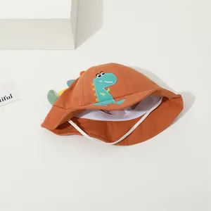 Close-up of caramel kids sun hat with green dinosaur embroidery and 3D colorful fins