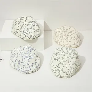 Détail de quatre casquettes crème pour enfants avec motifs de dinosaures colorés