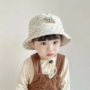 Detail of beige kids bucket hat with dinosaur print, LOVE YOU patch and adjustable strap