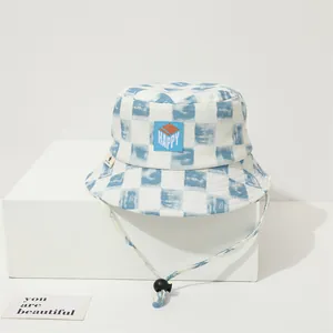 Detalle de gorro de pescador infantil a cuadros azules y blancos con parche HAPPY y cordón