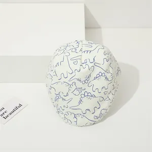 Détail d'une casquette gavroche blanche pour enfant avec motifs dinosaures bleus