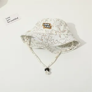Detailed top view of off-white toddler sun hat with brown dinosaur patterns and LOVE YOU patch