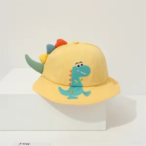 Close-up of yellow kids bucket hat featuring a green dinosaur patch and 3D colorful fins