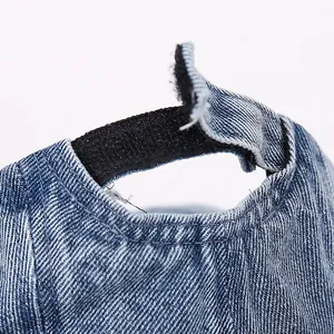 Detail of adjustable black hook and loop closure on a blue denim baby baseball cap