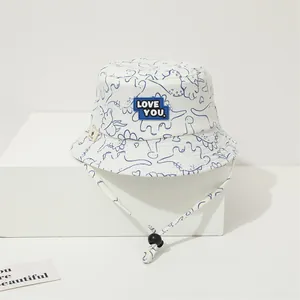 Detail of baby sun hat with blue dinosaur patterns and adjustable windproof chin strap