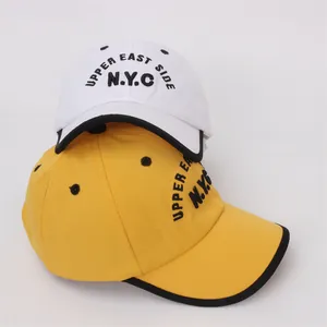 Detail of white and yellow kids' baseball caps with embroidered NYC text and contrast brim