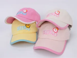 Détail de patchs brodés de dessins animés et passepoils contrastés sur casquettes enfant
