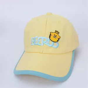 Détail de la casquette jaune avec passepoil bleu, broderie BEERUS et badge tigre