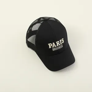 Detailed close-up of a black mesh trucker hat with Paris Original embroidery and curved brim