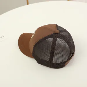 Side-view detail of dark brown mesh baseball cap with white embroidery and curved brim