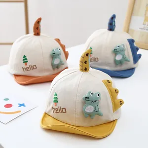 Détail de trois casquettes bébé en coton aux couleurs vives avec dinosaures 3D et broderie