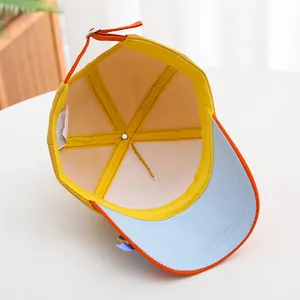 Detail of adjustable orange strap and silver buckle on a yellow cotton kids baseball cap