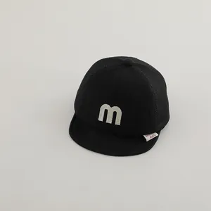 Close-up of black mesh baby baseball cap with white M letter embroidery and texture