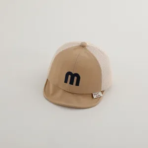 Detail of khaki baby mesh baseball cap with blue embroidered letter M and sun visor