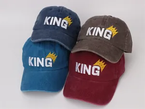 Top view of four washed cotton kids baseball caps with embroidered KING logo in multiple colors