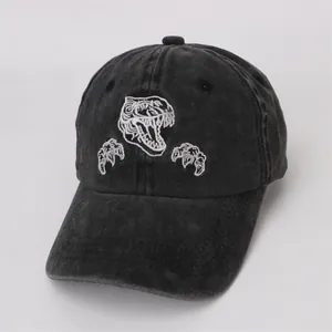 Détail de la broderie de dinosaure blanc sur une casquette de baseball noire pour enfant