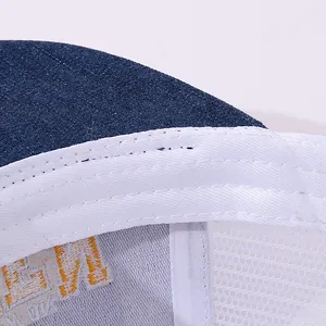 Detail of blue denim brim and white mesh back with reinforced stitching on baseball cap