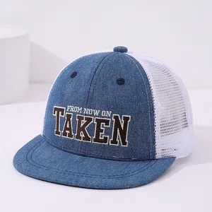 Macro view of blue denim flat brim and 3D TAKEN embroidery on breathable trucker hat