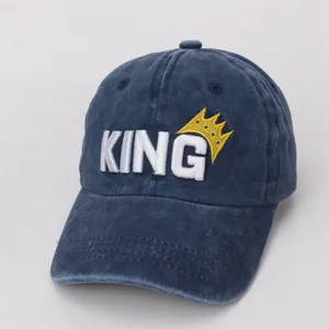 Detail of white KING embroidery and yellow crown on navy blue cotton baseball cap