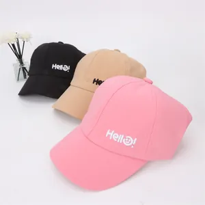 Détail de trois casquettes de baseball rose, beige et noir avec broderie Hello