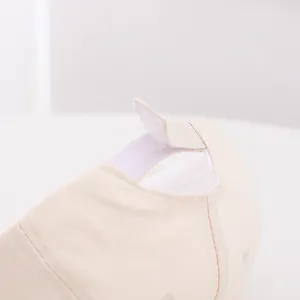 Detail of adjustable hook and loop fastener on beige cotton baby baseball cap