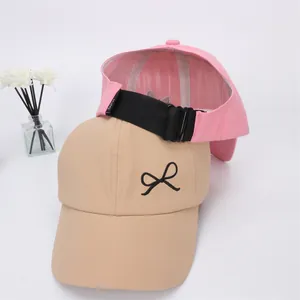 Détail de la boucle noire réglable et de la broderie de nœud sur les casquettes rose et kaki