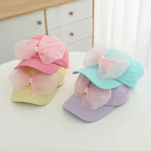 Detail of girls' sun visors with mesh bows and pearl accents in multiple candy colors