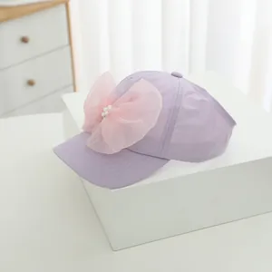 Detail of lavender kid baseball cap featuring a large pink tulle bow and pearl accents