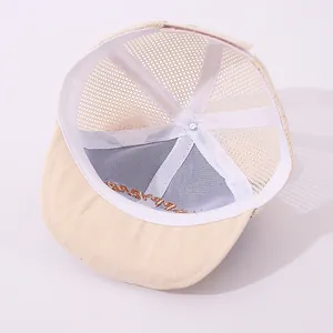 Detail view of the breathable mesh back and inner sweatband of the cream baby trucker hat