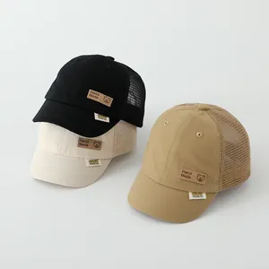Detailed view of mesh kids baseball caps in black, cream, and khaki with bear patches